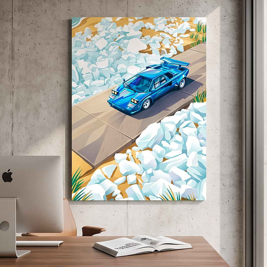 A vertical canvas wall art print featuring a stylized blue sports car on a bridge over white rocks, displayed on a concrete wall above a wooden desk with a computer monitor and an open book.